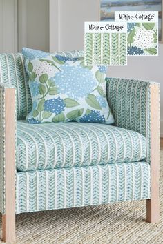 an upholstered chair with blue flowers and green leaves on the pillow is shown