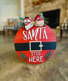 a wooden sign that says santa stop here with a bow on it's head