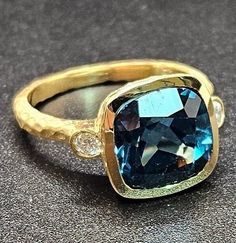 14k solid yellow gold hammered ring with 0.17 ct. SI1 clarity, G color natural brilliant diamonds & 7.70 ct. 11x11 mm cushion shape AAA natural London blue topaz. This item can also be ordered in rose or white gold with different color gemstones such as blue topaz, citrine, amethyst, green amethyst, pink amethyst, smoky quartz, white topaz, garnet, peridot, morganite & aquamarine. Please contact me for a quote as each gemstone varies in price. I am a manufacturer of fine jewelry for over thirty Elegant Hammered Diamond Rings, Hammered Ring, Hammered Rings, Pink Amethyst, Green Amethyst, Bezel Diamond, London Blue Topaz, London Blue, Brilliant Diamond