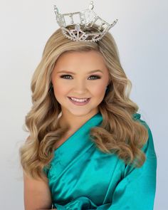 a woman wearing a tiara smiling at the camera with her hands on her hips