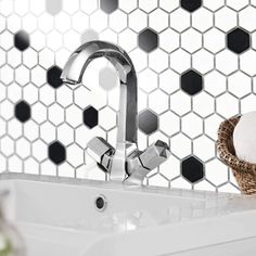 a white sink sitting under a faucet next to a basket filled with towels