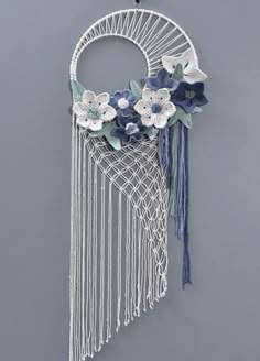 a white macrame with blue flowers and tassels hanging on the wall