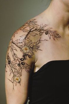 a woman's shoulder with flowers and leaves on her left arm, tattoo style