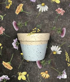 a flower pot sitting on top of a floor next to a wall covered in flowers