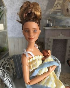 a doll is sitting in a chair with a towel on it's back and holding a baby