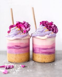 two desserts with purple frosting and pink flowers on top are sitting next to each other