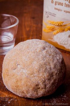 a loaf of bread sitting on top of a wooden table next to a bag of flour