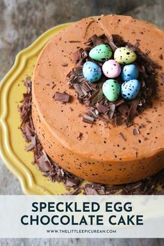 a cake with chocolate frosting and decorated eggs on top, sitting on a yellow plate