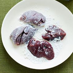 three pieces of meat on a plate with powdered sugar