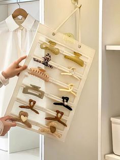 a person is holding up a display case with clothes pins and shoes on it in front of a white toilet