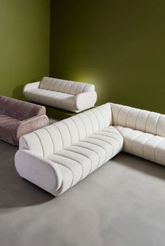 a living room with two couches and a chair on the floor in front of a green wall