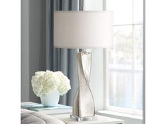 a lamp that is sitting on a table next to a vase with flowers in it