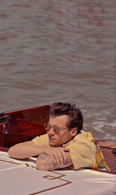 a man sitting on the back of a boat with his arms crossed and eyes closed