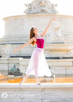 a woman is dancing in front of a fountain