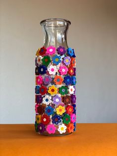 a glass vase with flowers on it sitting on top of a wooden table next to a wall