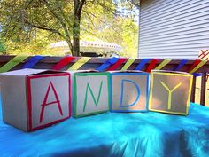 three blocks that spell out the word andy on top of a blue cloth covered table