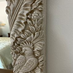 a decorative mirror with a bird and flower design on the front, next to a bed