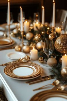 the table is set with gold and white plates, silverware, candles and christmas decorations