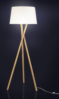 a wooden floor lamp with a white light on it's side and a black background