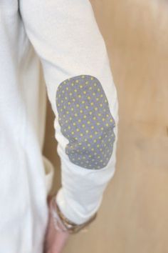 a person wearing white and yellow polka dots on their arm sleeves, holding a cell phone