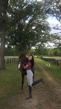 a woman is hugging a horse on the side of a road in front of a tree