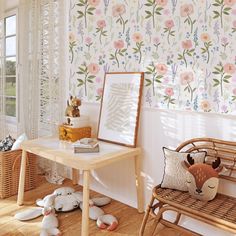 a wooden bench sitting next to a table with stuffed animals on top of it in front of a floral wallpaper