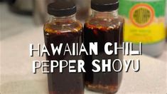 two bottles filled with food sitting on top of a counter next to a bottle of pepper