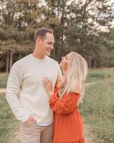 a man and woman are standing in the grass smiling at each other as they stand close together