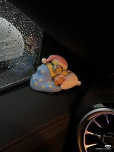 a small figurine is sitting on the dashboard of a car in the rain