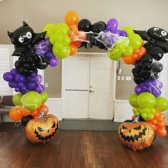 an arch made out of balloons with cats and pumpkins on it in the middle of a room