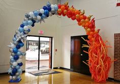 an arch made out of balloons in the middle of a room with a door open