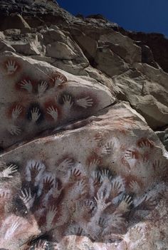 many hand prints on the rocks with blue sky in background