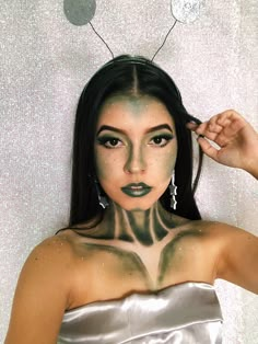 a woman with black and white makeup is posing for the camera while holding her hair in front of her face