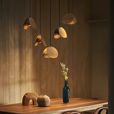 a wooden table topped with a vase filled with flowers and lights hanging from the ceiling