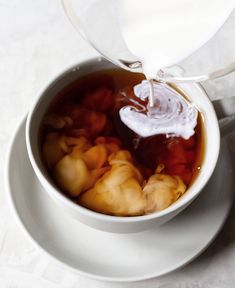 someone pouring milk into a cup filled with food