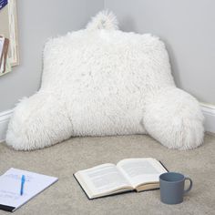 a book and cup on the floor next to a pillow