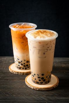 two drinks sitting on top of wooden coasters next to each other, one is orange and the other has black dots