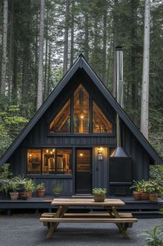 a small cabin in the woods with a picnic table and lights on it's windows