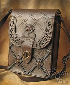 a brown leather purse sitting on top of a bed