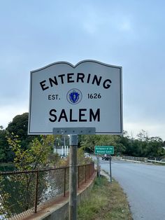 a white sign that reads entering salem on the side of a road next to a fence