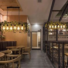 an empty restaurant with wooden tables and hanging plants on the wall, along with seating