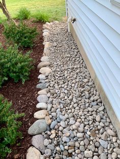 a rock garden bed next to a white house