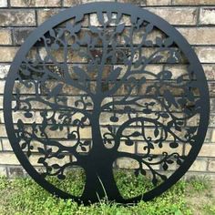 a metal tree sculpture sitting in front of a brick wall