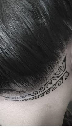 a woman's neck with a black and white tattoo design on her left side