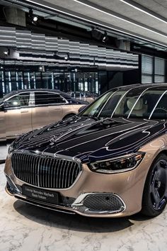 two cars are parked in an empty parking garage, one is beige and the other is black