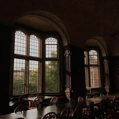 an empty room with many tables and chairs in front of two large windows that look out onto the trees outside