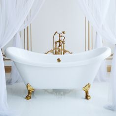 a white bathtub with gold fixtures and curtains