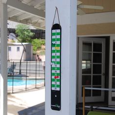 a thermometer hanging on a wall next to a swimming pool and patio area