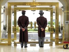 two men in top hats and tails standing at the entrance to a building