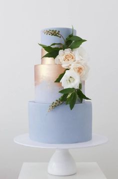 a three tiered blue cake with flowers on top and the words instagram above it